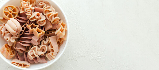 Fototapeta na wymiar Pink Italian pasta in white bowl on a light background. Concept alternative pasta. Horisontal orientation. copy space. Top view. Banner