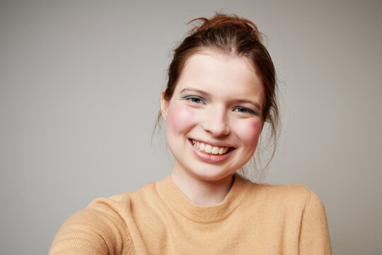 Cheerful woman taking selfie in studio