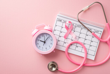 Breast cancer awareness concept. Top view photo of pink ribbon calendar alarm clock and stethoscope on isolated pastel pink background