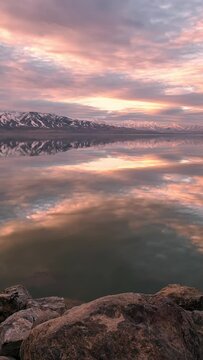 Reflection of clouds moving over the surface of Utah Lake in timelapse during sunset viewing the pattern and texture of the sky.