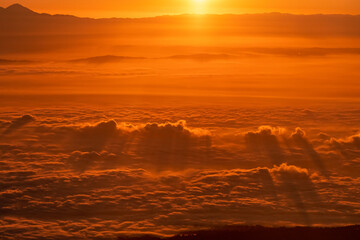 Fototapeta na wymiar Aerial view of sunrise above the clouds with mountains in the background