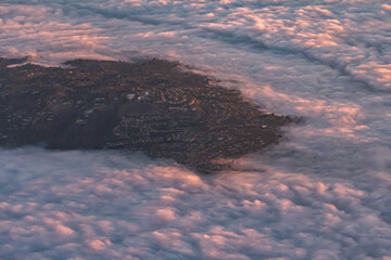Aerial view of a Mountain top Neighborhood looking over low clouds at sunrise in Southern California