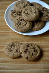 Delicious oatmeal cookies with chocolate chips on a white plate on a mat. Sweet oatmeal cookies close-up.