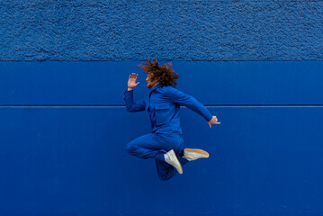 Man in blue clothes jumping against wall