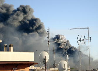Grande nuvola di fumo nero, incendio dietro edifici in città