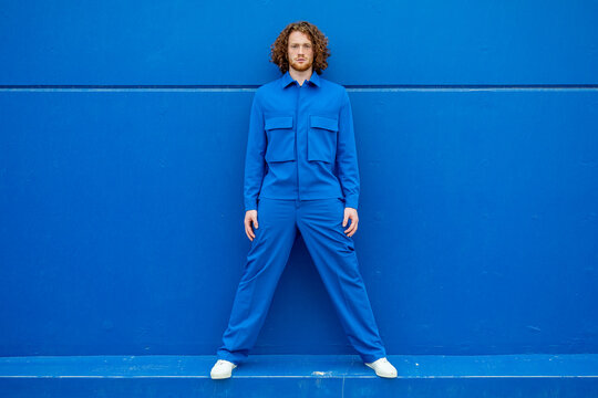 Redhead man in blue clothes with legs apart