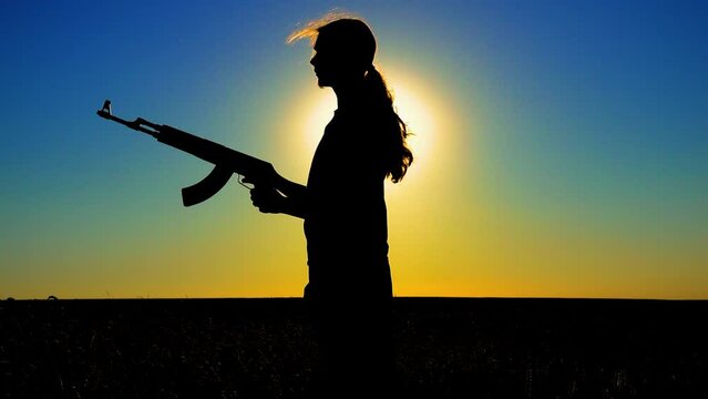 Ukraine War. A young man with a Kalashnikov assault rifle trains in the field. Silhouette of a man with a Kalashnikov assault rifle. The concept of war, terrorism, aggression against Ukraine.