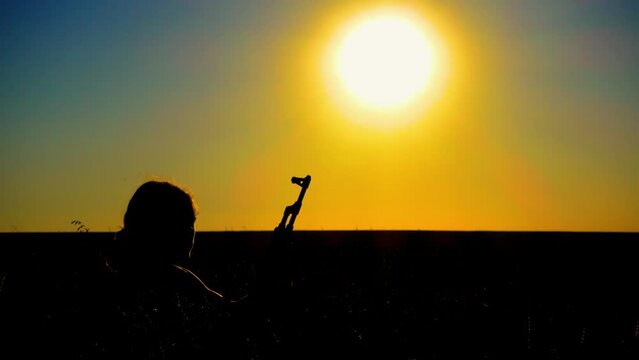 Ukraine War. A young man with a Kalashnikov assault rifle trains in the field. Silhouette of a man with a Kalashnikov assault rifle. The concept of war, terrorism, aggression against Ukraine.