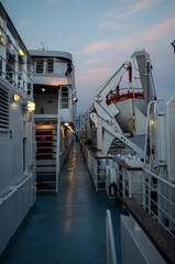 Cruise ship deck for tourists. Ferry with lifeboat and iron steps.