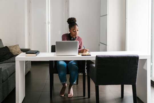 Self employed lady taking notes during work at home