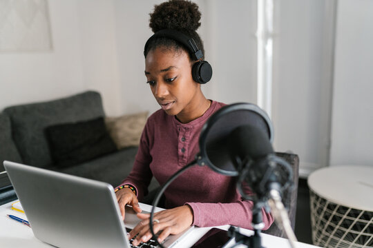 Black lady working online on laptop in light room
