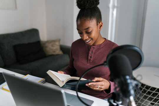 Happy black lady reading book while preparing for exams