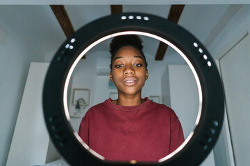Black woman sitting in front of ring lamp