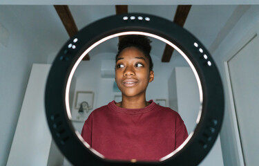 Black blogger in front of ring lamp at home