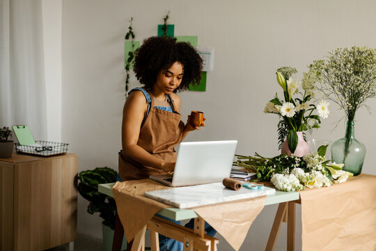 Florist working with laptop at small flower studio
