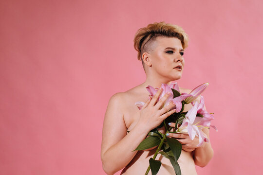 Real body type woman posing with flowers on pink background 