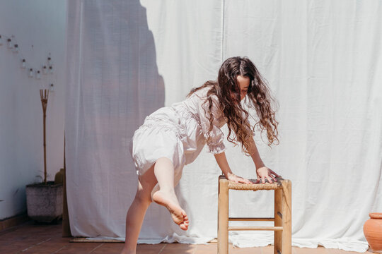 Barefoot girl in white dancing at terrace