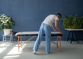 Massage therapist covering table with sheet