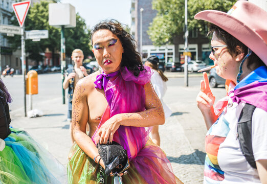 Man in a dress and a woman in cowboy hat smoke during Pride