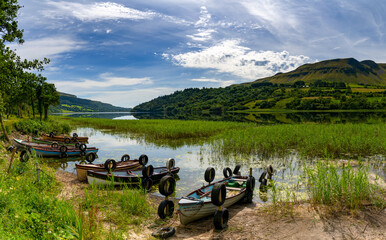 Fototapeta na wymiar Glencar Lough landscape with many colorful small wooden fishing boats on the lakeside