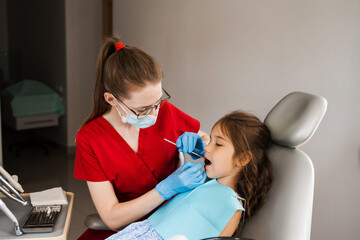 Pediatric dentist examines teeth of child girl for treatment of toothache. Pain in teeth in children. Consultation with pediatric dentist in dentistry.