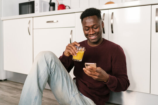 African American man with juice using smartphone