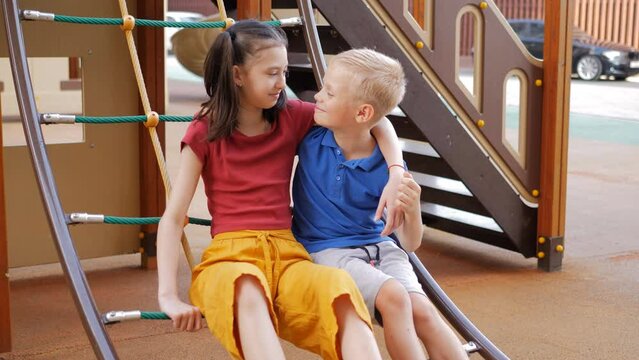 Romance in childhood. A boy and a girl on the playground cuddling flirting.