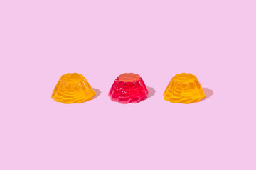 Three red and yellow jelly pudding over pink background