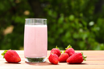 Strawberry smoothie or milkshake against lush folliage. Summer drinks, outdoor. Selective focus