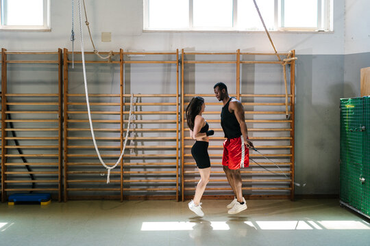 Diverse couple exercising with skipping rope in gym
