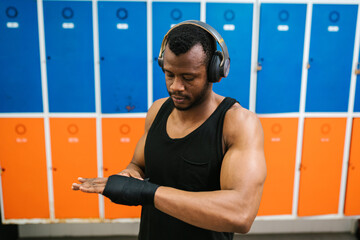 Black man wrapping hand with boxing bandage in gym
