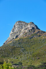 Copyspace landscape view of the top of a mountain during the day in summer from below. Scenic bottom view of a natural landmark against a clear blue sky. Nature and ecology in the green countryside
