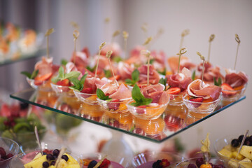 Catering on wedding. Wedding banquet table. Sweet table with fruit. Fruit bar on party. Delicious fruits appetizers. Tasty desserts, cakes and pastry on the wedding sweet buffet.