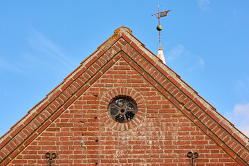 View of a round window on an old red brick wall of a house or home. Glass with metal frame on historic church building. Architecture design and details on a city structure outside with copy space