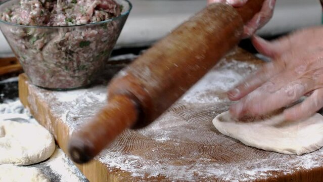 Human hands roll out fresh dough for make bread or pizza on kitchen board for baking.