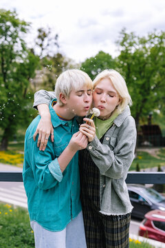 Couple in love puffing together on dandelion seeds 