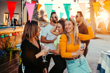 Joyful friends dancing during beach party at sunset