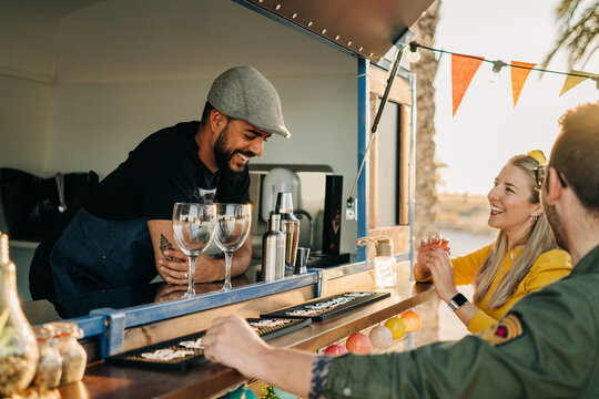 Smiling food truck barman and clients chatting together