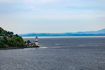 Small lighthouse on British coast with mountain ranges visible on a distance behind the fog in the air.
