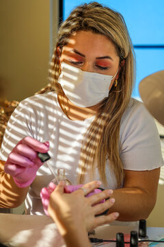 A manicurist applies oil on woman's nails and cuticles in beauty salon