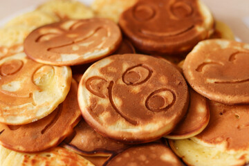 Funny pancakes with smiley faces close-up. Breakfast idea. Selective focus