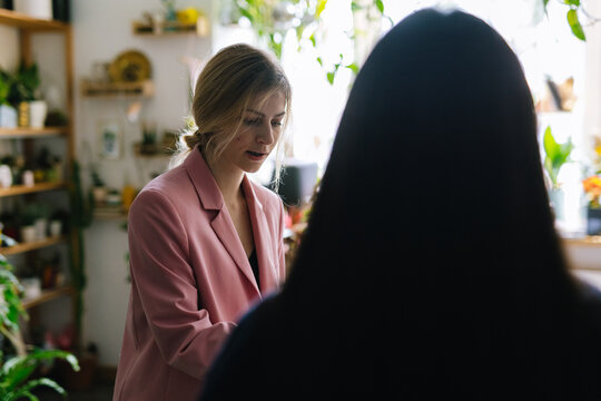 Woman having conversation with seller in floral store 