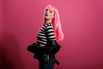 Portrait of beautiful lady looking at camera in studio, posing with natural leather jacket and pink...