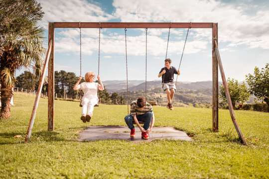Mother and sons having fun on the swings