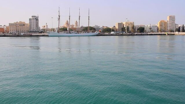 Arriving by boat at the Port of Cadiz with a view of the sailing ship Juan Sebastian Elcano anchored in front of the cathedral