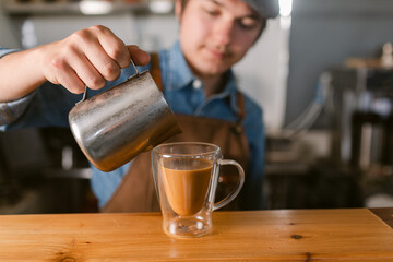 Crop barista serving steamed milk on coffee