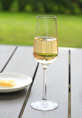 A glass of dry white wine is on the table. It's a summer day