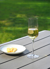 A glass of dry white wine stands on a table in the garden. Summer day