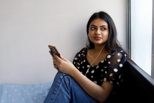 Young woman listening to music on mobile phone indoors