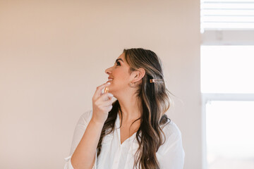 Latin smiling woman putting on perfume